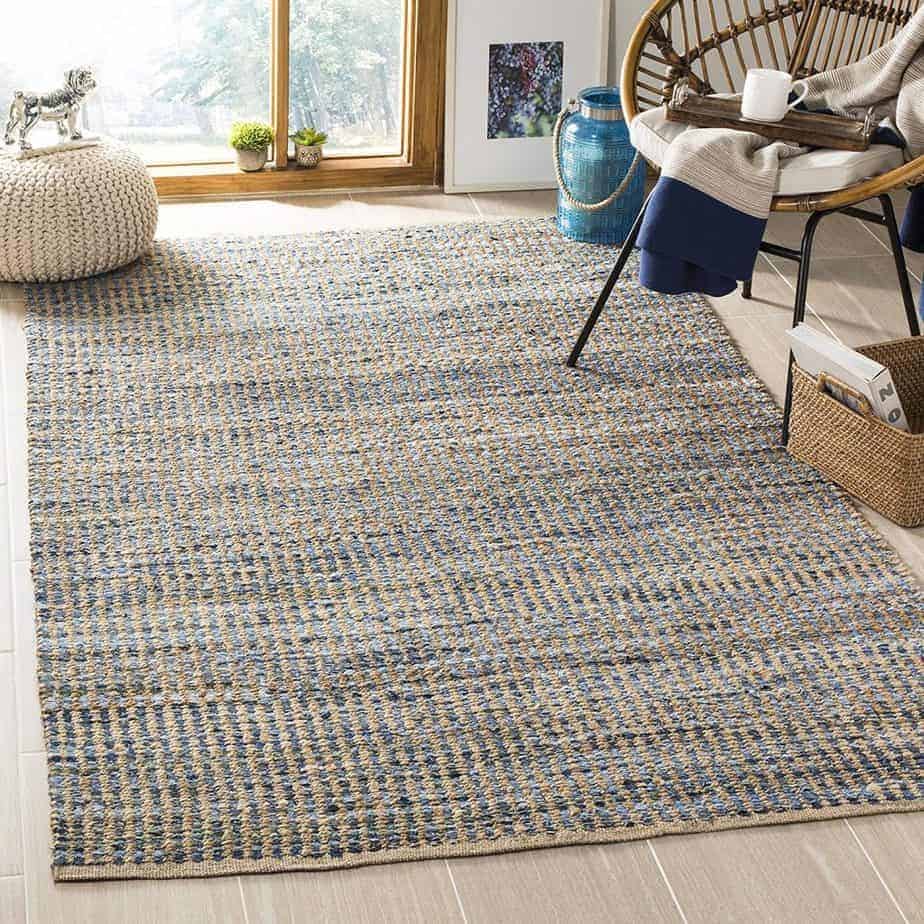 A blue and cream jute rug in a living room with a wooden chair and decor.