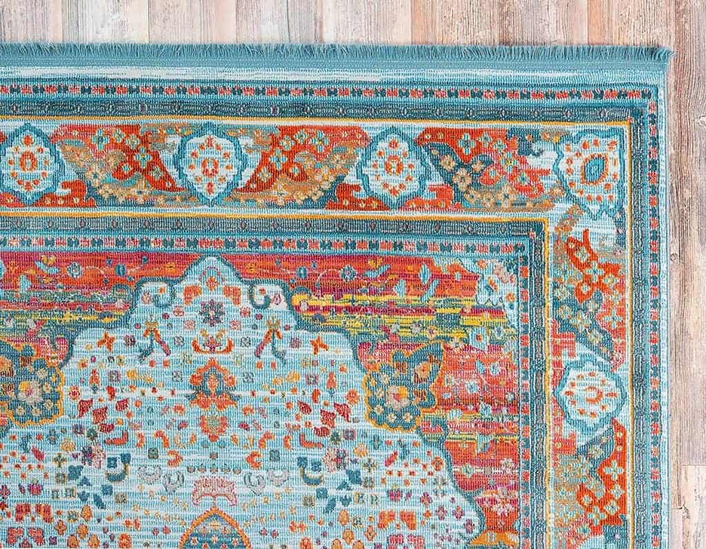Close-up of a teal and orange area rug on a light wood floor.